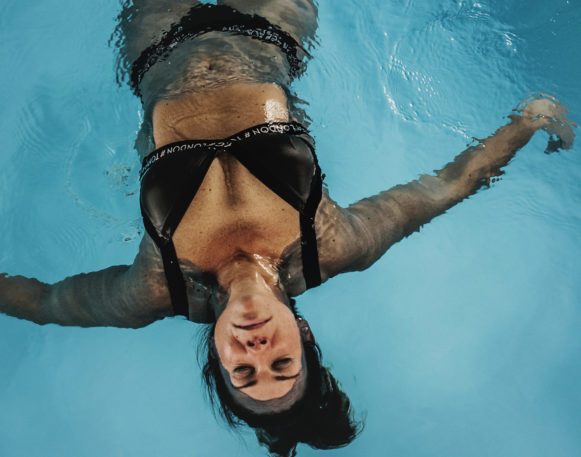 bildet viser kvinne flyte avslappende på ryggen i basseng.