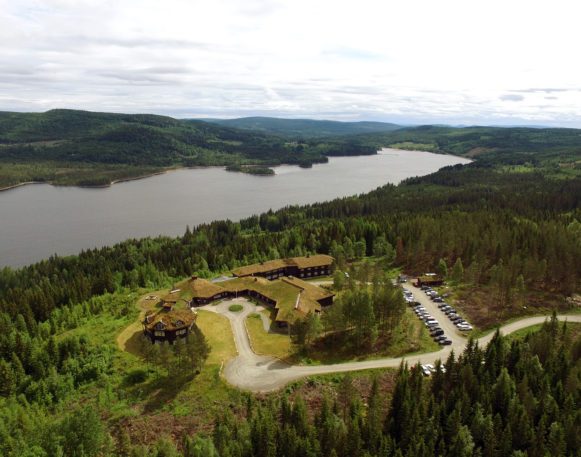 oversiktsbilde av Finnskogtoppen Spa og Velværehotell fra fugleperspektiv med innsjøen Røgden i bakgrunnen.
